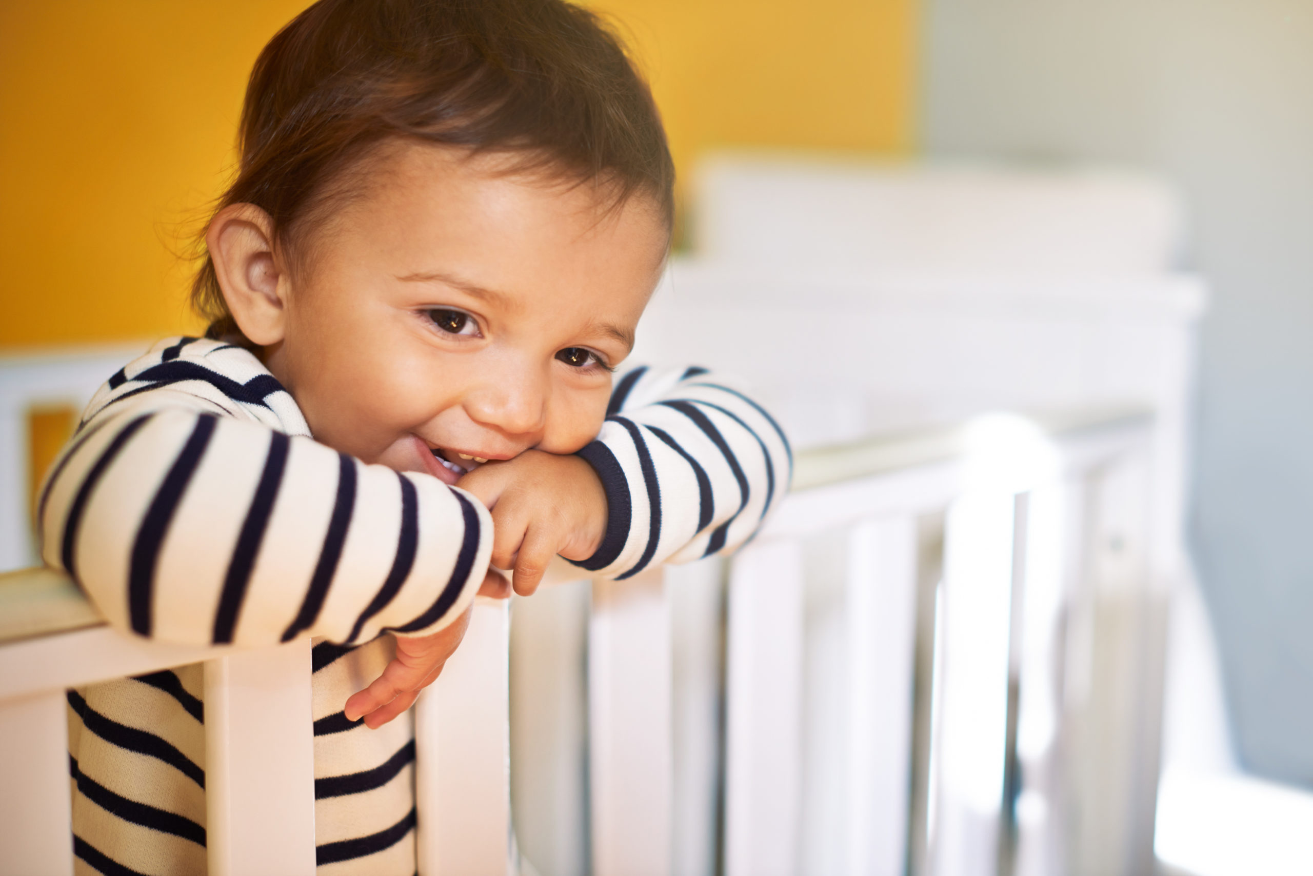 Cropped shot of an adorable baby girl standing in her crib at home during the 14-month sleep regression