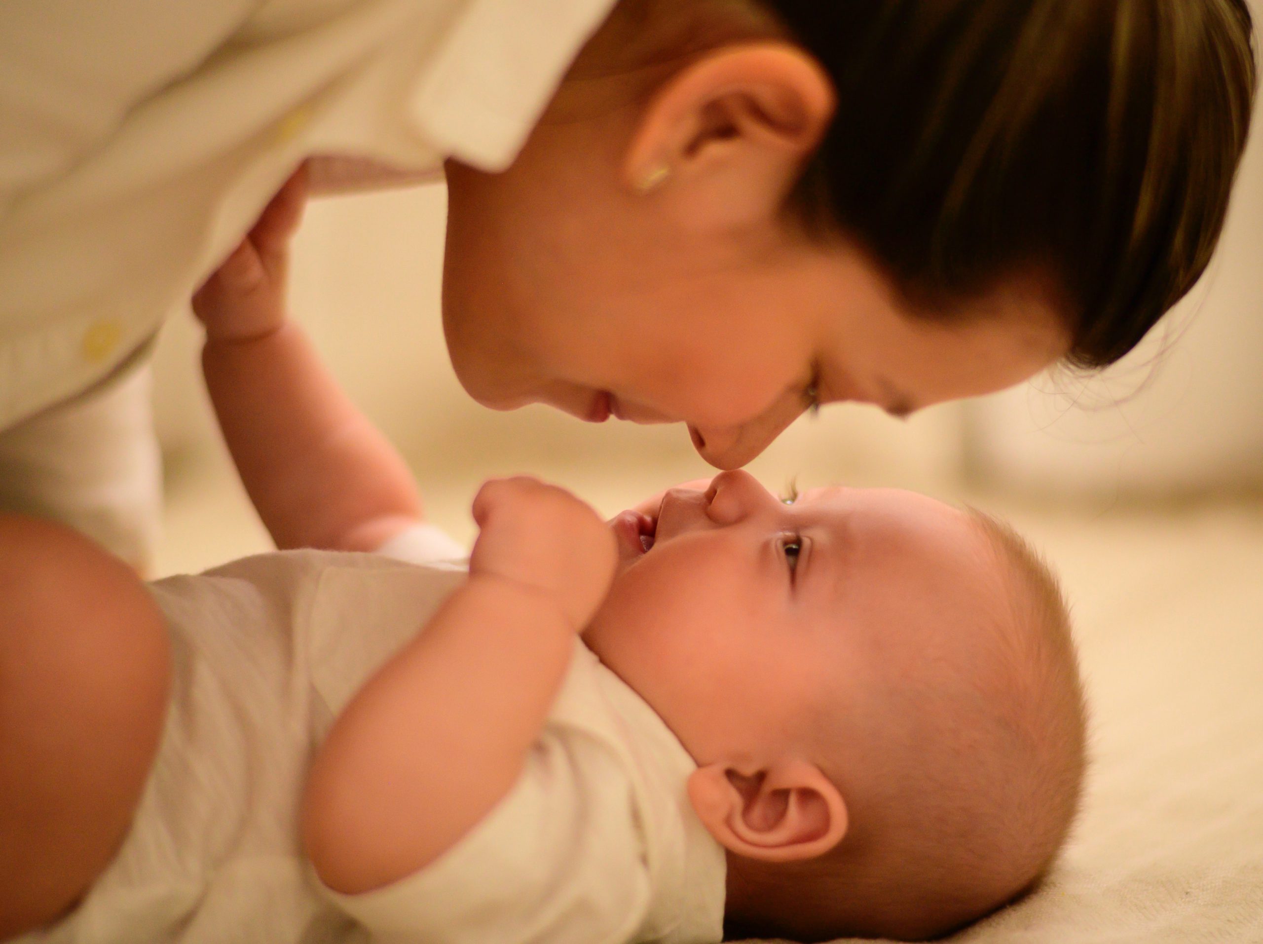 A mother playing with her baby. They're nose to nose.