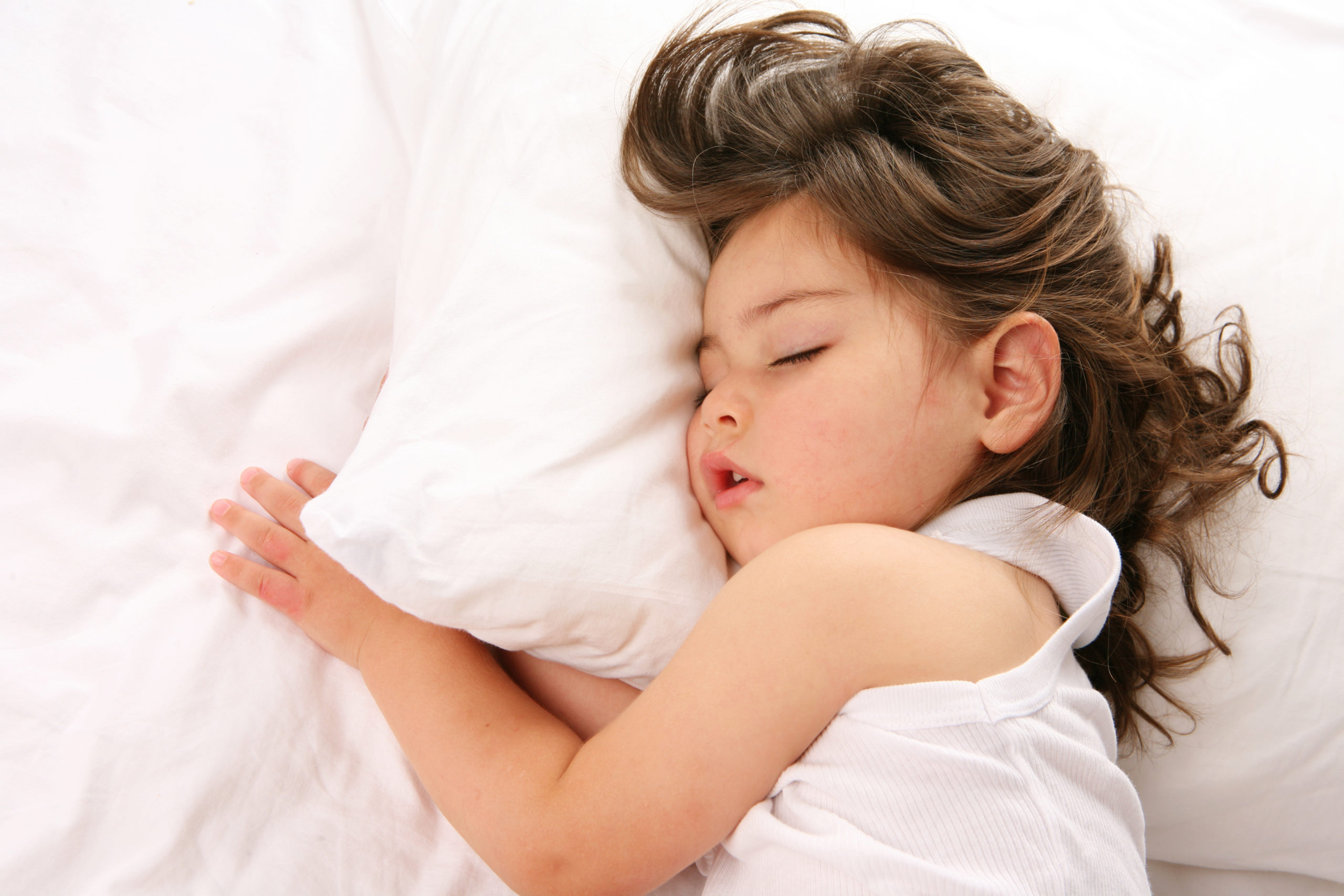 A sleeping preschool-aged child with her head on a pillow