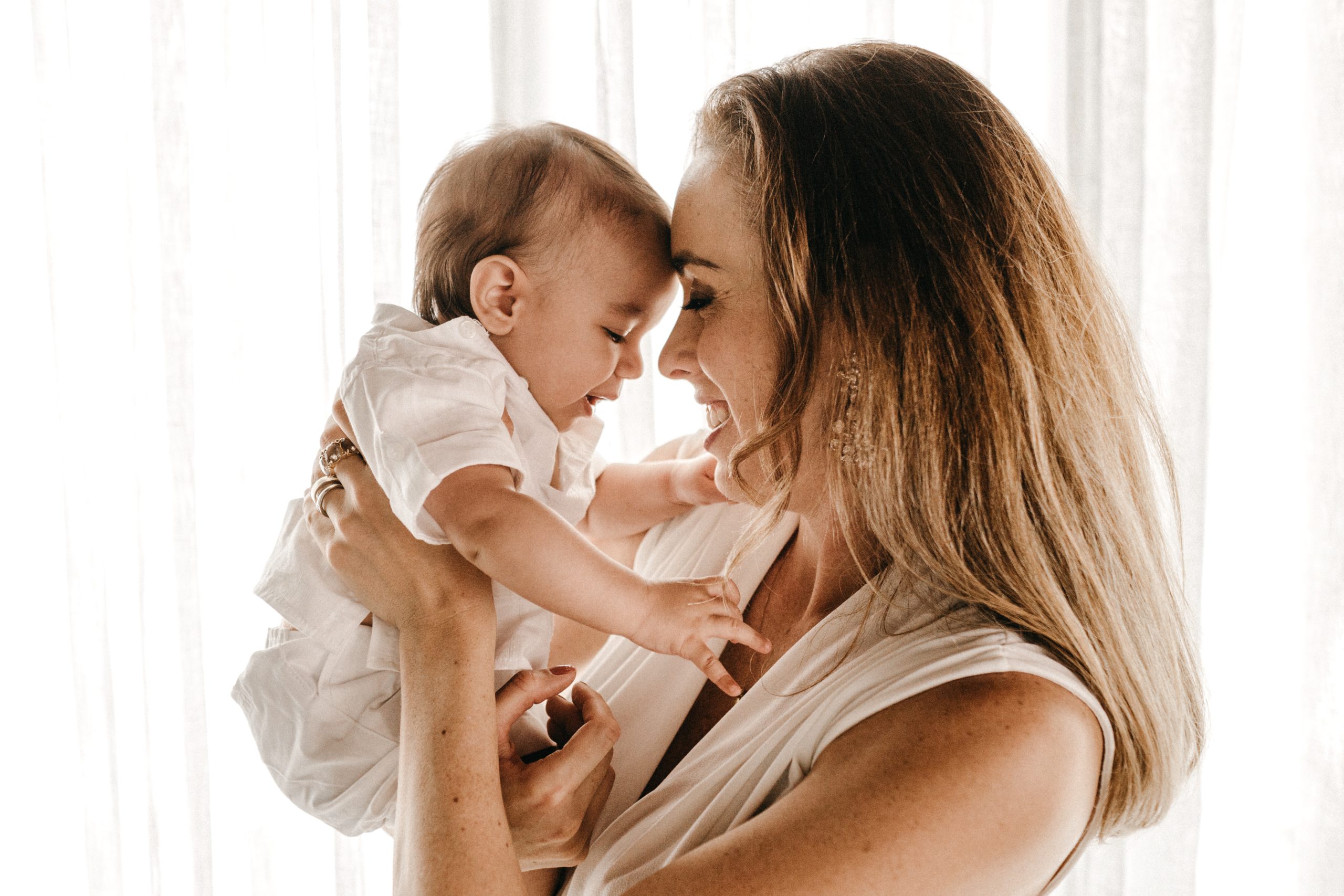Mom holding her baby forehead to forehead smiling.
