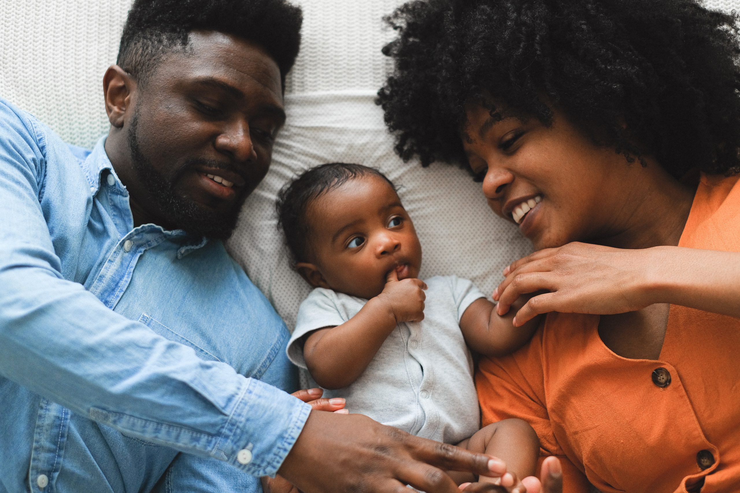 Cute family resting with their 5-month-old baby between them.